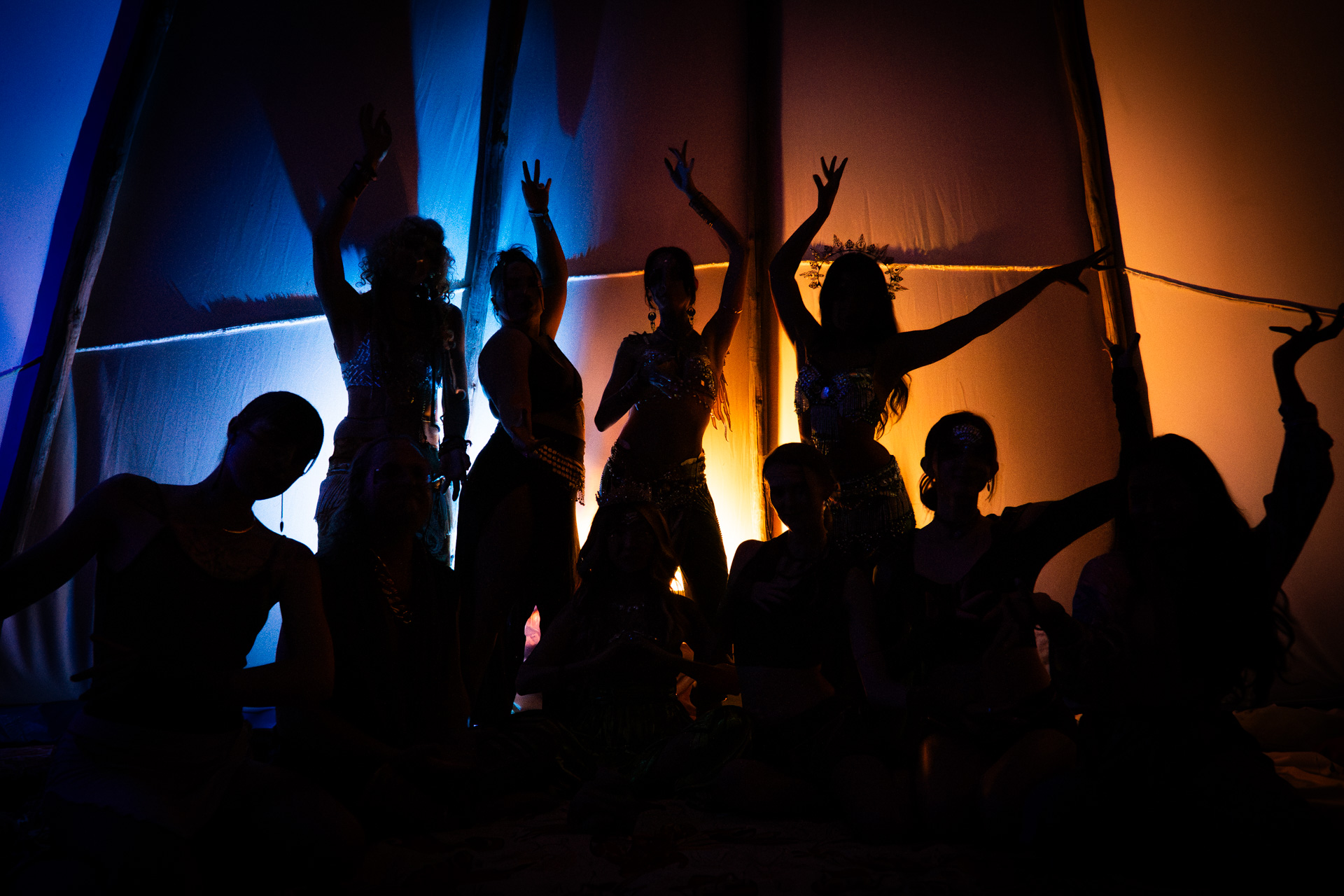 silhouetted dancers striking poses inside a colorful tipi at the Medicine for the People spiritual gathering near Austin, Texas